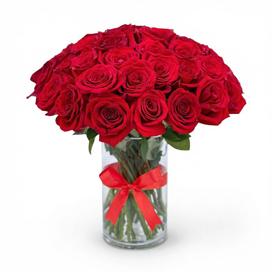 50 fresh red roses arranged in a clear glass vase with a red ribbon, perfect for gifting in Kuwait.