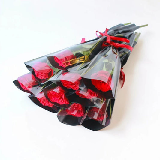Bouquet of red roses wrapped in clear plastic on a white background