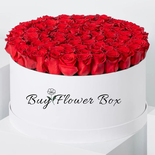 Red roses arranged in a white round hat box flower arrangement
